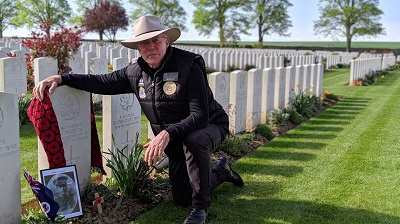 Mr Kerry Finch kneeling at the grave of Corporal Michael Manion