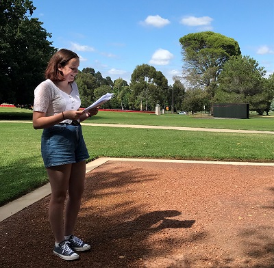 A young woman reading a report in a park 