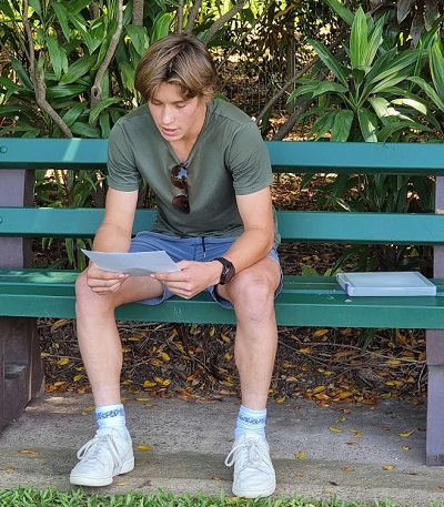 Lachlan Rogers reading research while seated on a park bench