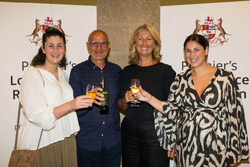 Four attendees at the southern 2025 event pose clinking champagne glasses in front of event banners