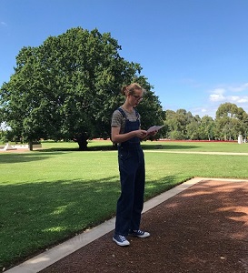 Noah Gladdish reading a report while standing in a park