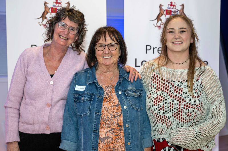 An award recipient poses with two family members at the northern event in 2025