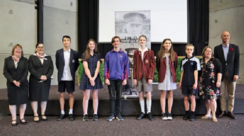 A group of people standing in a line with a black and white banner behind them.