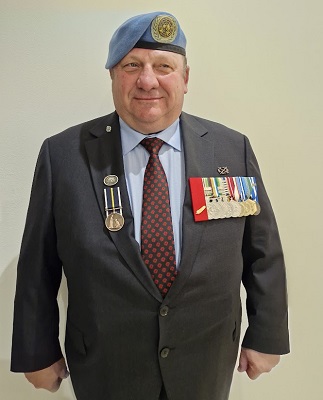 A man wearing a blue beret and suit jacket with military medals