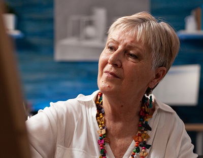 A woman with grey hair doing a painting