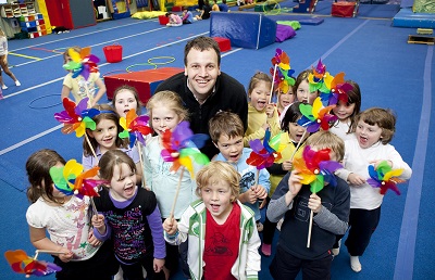 A volunteer with children holding windmills