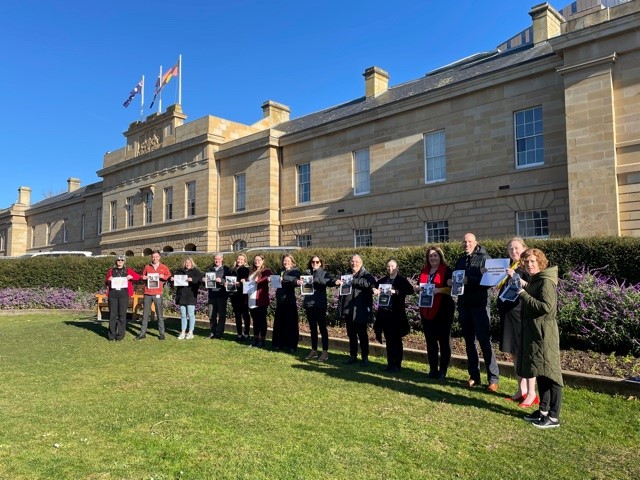 DPAC staff in front of Parliament House all holding their pledges for change